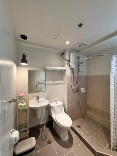 a bathroom with a toilet and a sink and a shower at Cozy Cove - Avida Aspira Tower 1 in Cagayan de Oro
