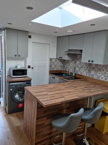 a kitchen with a wooden counter with two bar stools at Studio in Raynes Park