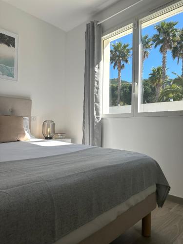 - une chambre avec un lit et 2 fenêtres avec des palmiers dans l'établissement Villa neuve avec piscine 3 chambres 140 m2, à Calvi