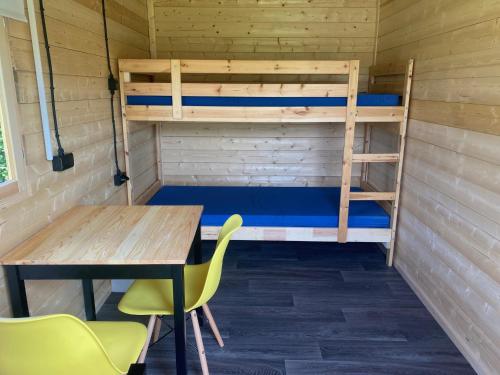 una stanza con letti a castello, tavolo e sedie di Woodland Cabin Camping de Regenboog a Šluknov