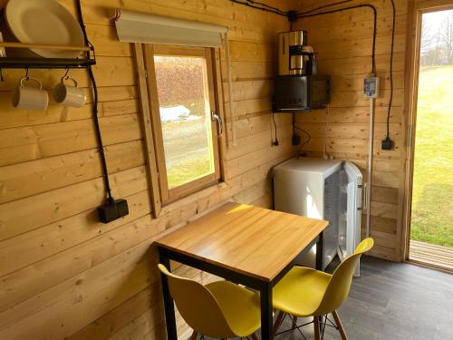 un tavolo e sedie in legno in una casetta minuscola di Woodland Cabin Camping de Regenboog a Šluknov