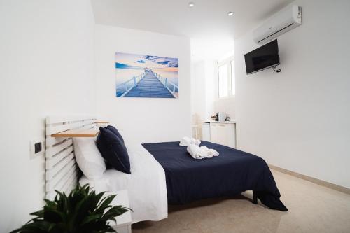 a white bedroom with a bed and a tv at Puglia Mar in Mola di Bari