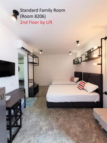 a bedroom with two beds and a desk and a tv at Mwv Family Suite Room in Muar