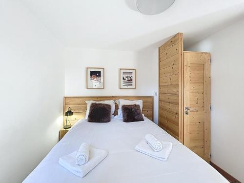 une chambre avec un grand lit blanc avec deux serviettes dans l'établissement Charme-appartement-6 pers-proche piste, aux Gets