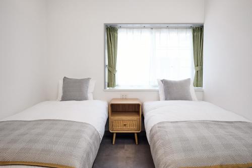 two twin beds in a room with a window at コートハウス三茶 in Tokyo