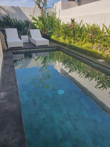 a swimming pool with two white chairs and water at New 2BR Villa Private Pool Near Seminyak in Kerobokan