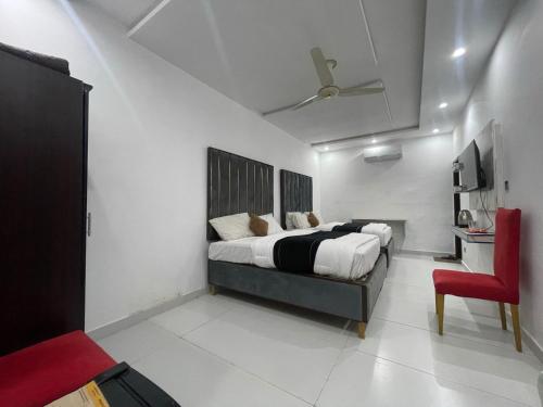 a bedroom with a bed and a red chair at Hotel Tulip Inn, Gulberg in Lahore