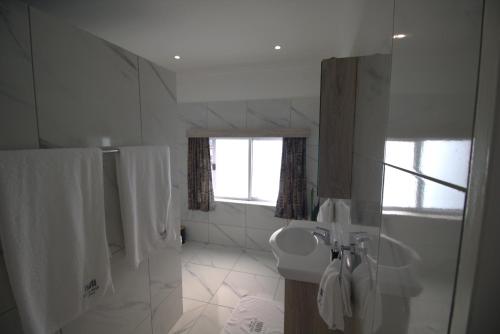 a white bathroom with a sink and a toilet at Little Bush Guesthouse in Omaruru
