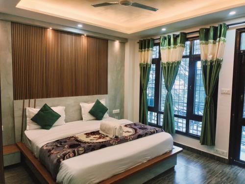 a bedroom with a large bed with green curtains at Hotel Green Forest View Mountain Touch in Shimla