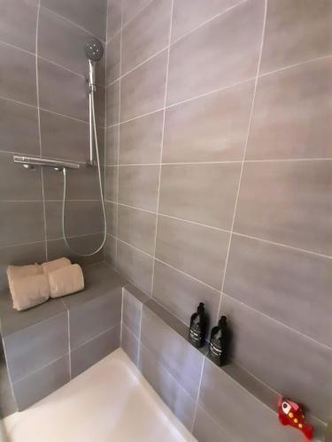 La salle de bains est pourvue d'une douche et d'une baignoire blanche. dans l'établissement Echappée Marine - Plage du Grau-du-Roi, au Grau-du-Roi