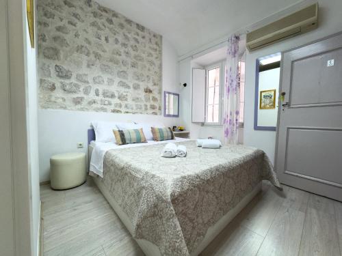 a bedroom with a bed with a stone wall at Cozy studio Lučić 1 i 2 in Dubrovnik