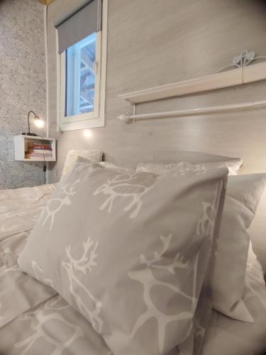 a white bed with white pillows and a window at Mummon Mökki in Lokka