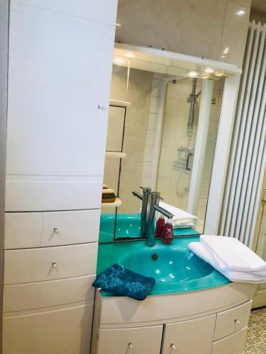 une salle de bain avec un lavabo bleu et un miroir dans l'établissement Villa Fenouil, à Binic