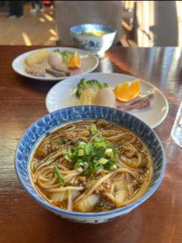 a bowl of noodle soup on a wooden table at 香格里拉喀玛美敦民宿 in Shangri-La
