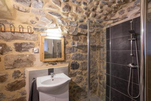La salle de bains en pierre est pourvue d'un lavabo et d'une douche. dans l'établissement Charmant T2 Centre historique, à Vals-les-Bains