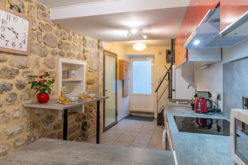 une cuisine avec un comptoir et un mur en pierre dans l'établissement Charmant T2 Centre historique, à Vals-les-Bains