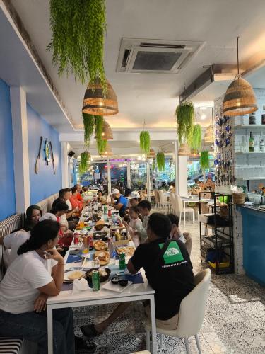 a group of people sitting at a long table in a restaurant at Fora Boutique Hotel in Karon Beach