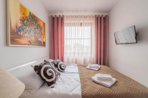 a bedroom with a bed with two pillows and a window at Horyzont Apartamenty- Apartament Nadmorski, blisko PKP i centrum in Kołobrzeg