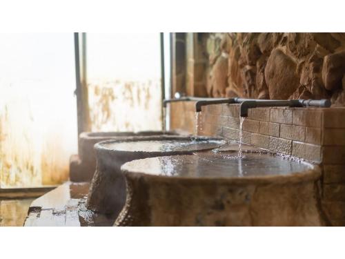 霧島市にあるMyoken Onsen Nemu - Vacation STAY 20867vの3つの洗面台があり、水が出る石造りのバスルーム