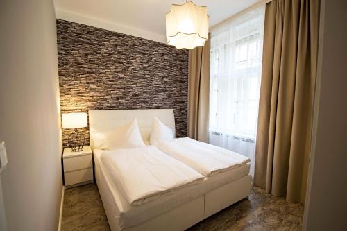 プラハにあるRuterra By Golden Lady's 3BDR Loftの白いベッドとレンガの壁が備わるベッドルーム1室が備わります。