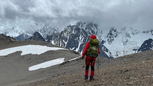 a person with a backpack standing on a mountain at 香格里拉喀玛美敦民宿 in Shangri-La