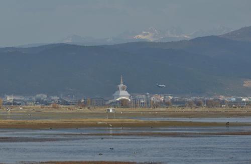 a plane flying over a body of water with a city at 香格里拉喀玛美敦民宿 in Shangri-La