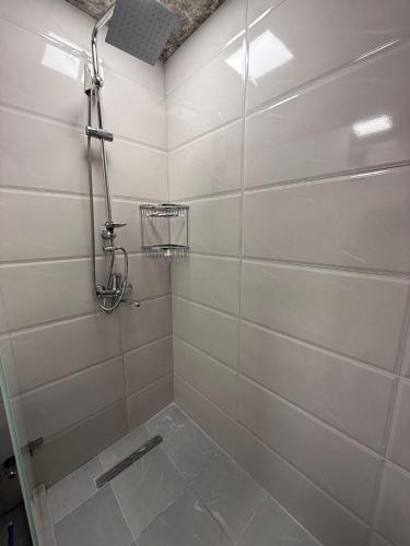 a white tiled bathroom with a shower stall at Qızıl Farel (Ailəvi İstirahət Mərkəzi) in İsmayıllı