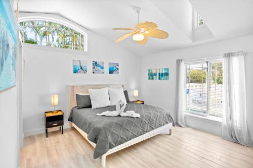 a bedroom with a bed with a ceiling fan and windows at Little Pink Houses in Anna Maria