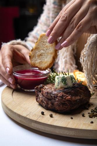 a person holding a piece of bread next to a hamburger at Hotel Prunk in Sežana