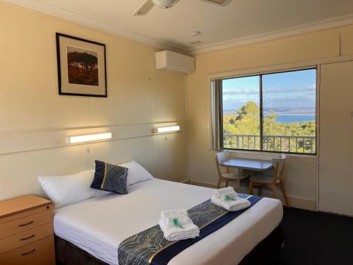 a bedroom with a bed and a window with a view at Bayview Motor Inn in Eden