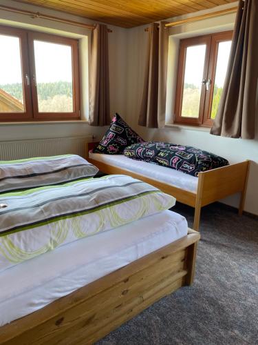 two beds in a room with two windows at Ferienwohnungen Paukner in Sankt Englmar