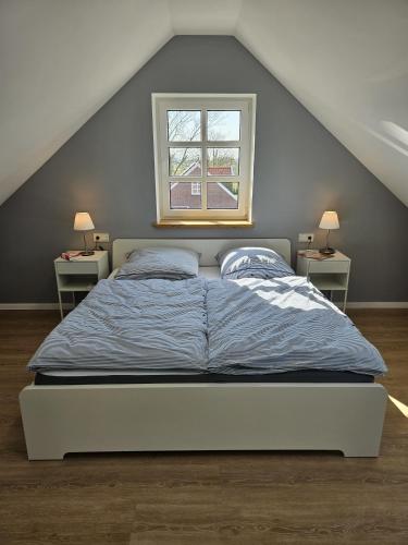 a bed in a room with two night stands and a window at Ferienhaus Mühle 5 in Krummhörn
