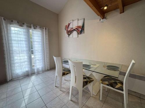 une salle à manger avec une table en verre et des chaises blanches dans l'établissement Maison 2 pièces -mezz CHATELAILLON PLAGE - CL080-029, à Châtelaillon-Plage