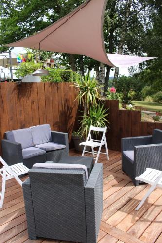a patio with chairs and an umbrella on a wooden deck at studio tout confort au coeur du parc Livradois forez in Cunlhat