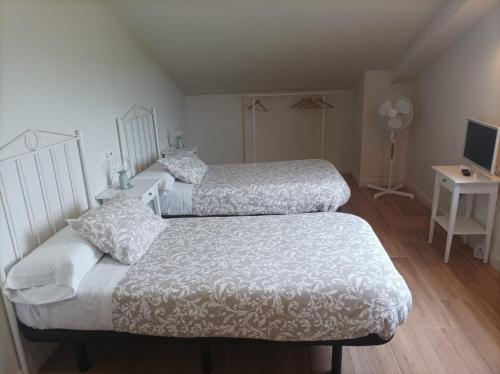 a bedroom with two beds and a desk with a television at La Rinconada in Castrojeriz