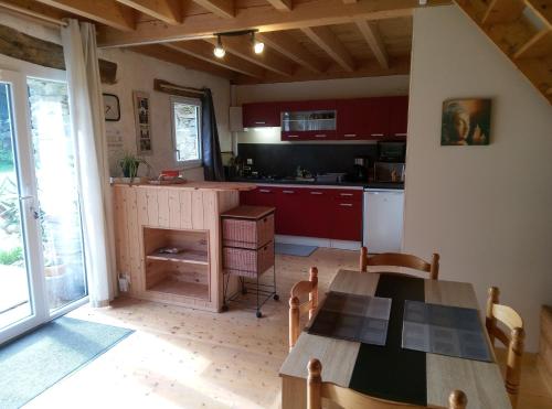 une cuisine avec des placards rouges et une table en bois avec une table. dans l'établissement Le Jardin Enchanteur, chaleureuse maison d'hôtes éco-responsable, calme et accueillante, à Lopérec