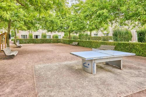 a picnic table and two benches in a courtyard at Résidence Pierre & Vacances le Green Beach in Port-en-Bessin-Huppain
