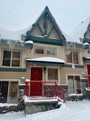 a house with a red fence in the snow at Townhouse, Ski in Ski out in Big White