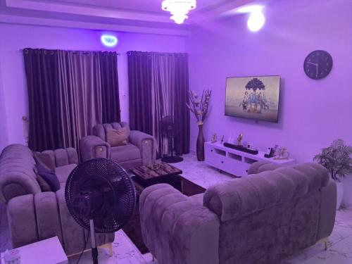 a purple living room with couches and a fan at Comfort Homes - Cozy Apartment in Egbeda in Okunola