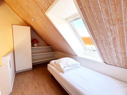 a attic bedroom with a bed and a window at Skagen Strand Holiday Center in Hulsig