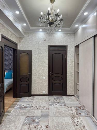a hallway with two brown doors and a chandelier at AlaNest Apartment in Bishkek