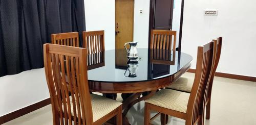 a dining room table with chairs and a glass vase on it at Diya Homestay Mamalakandam in Mamalakandam