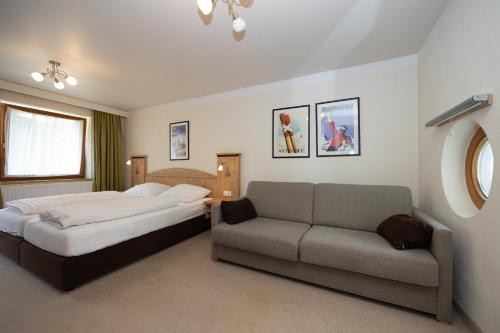 a bedroom with a bed and a couch at Pension Appartments Christoph in Westendorf