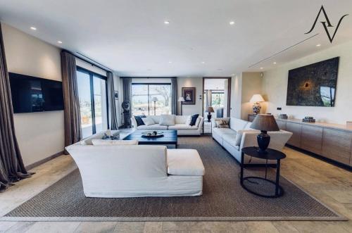 Elle comprend un salon doté d'un mobilier blanc et de grandes fenêtres. dans l'établissement Villa Velar, à Saint-Tropez