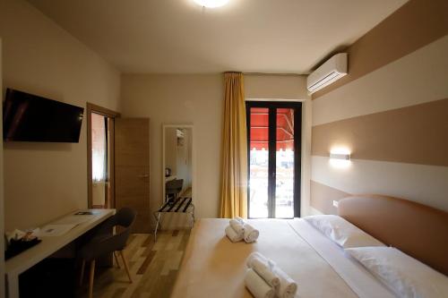 a hotel room with a bed and a desk and a window at Hotel Primavera in Peschiera del Garda