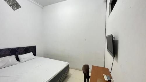 a bedroom with a bed and a table with a television at Hotel O Kost Biru in Makassar