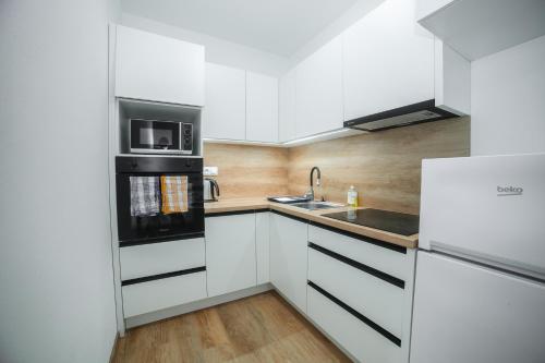 a white kitchen with a sink and a microwave at apartmány MAJKA in Holíč