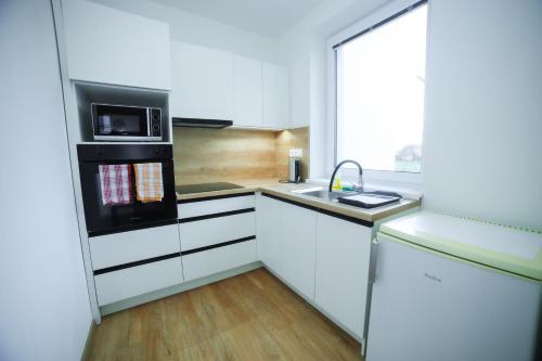 a kitchen with white cabinets and a sink and a microwave at apartmány MAJKA in Holíč