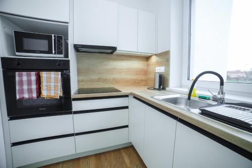 a white kitchen with a sink and a microwave at apartmány MAJKA in Holíč