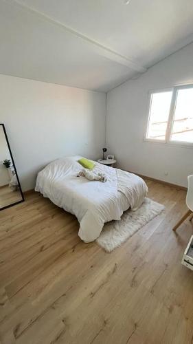 une chambre blanche avec un lit et un parquet dans l'établissement Villa Beau Soleil, à Aytré